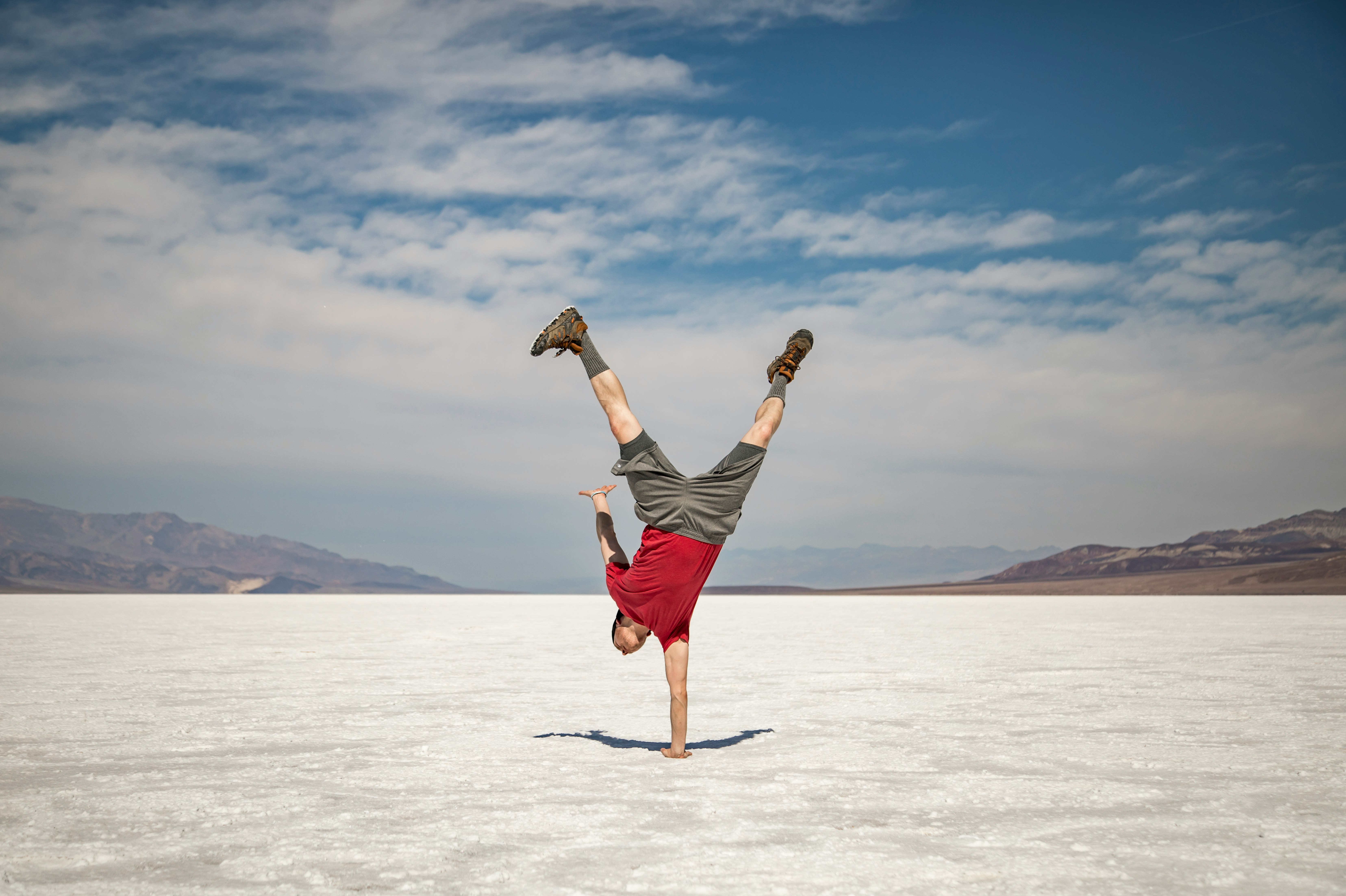 woman in black shirt and red shorts jumping on white sand during daytime